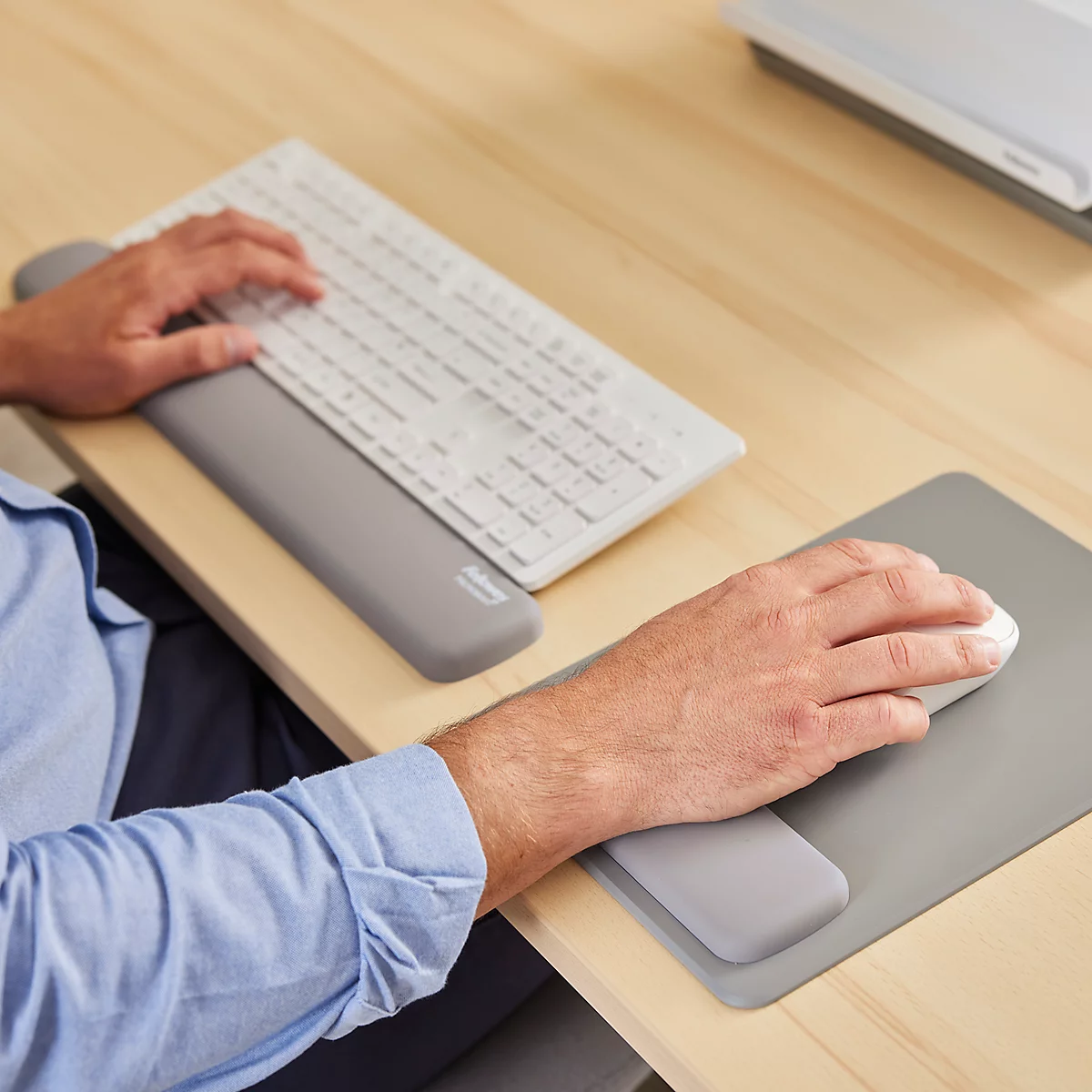 Grijs muismat met polssteun en zwarte muis. Fellowes-logo rechtsboven.