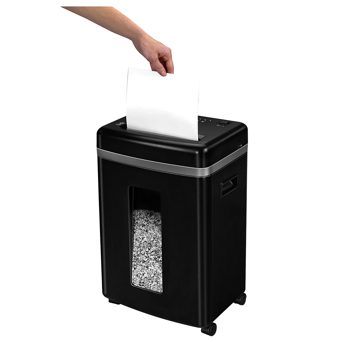A hand inserting a white sheet of paper into a black paper shredder. Shredded paper is visible below.