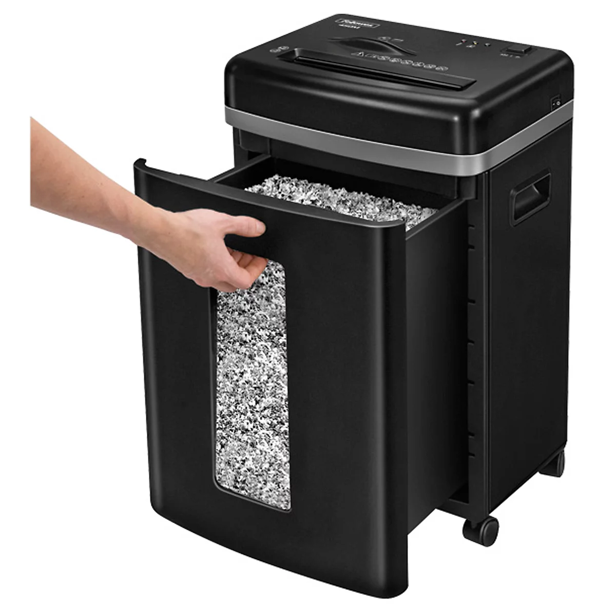 A black paper shredder with the collection container pulled out. A man's hand is emptying the container.