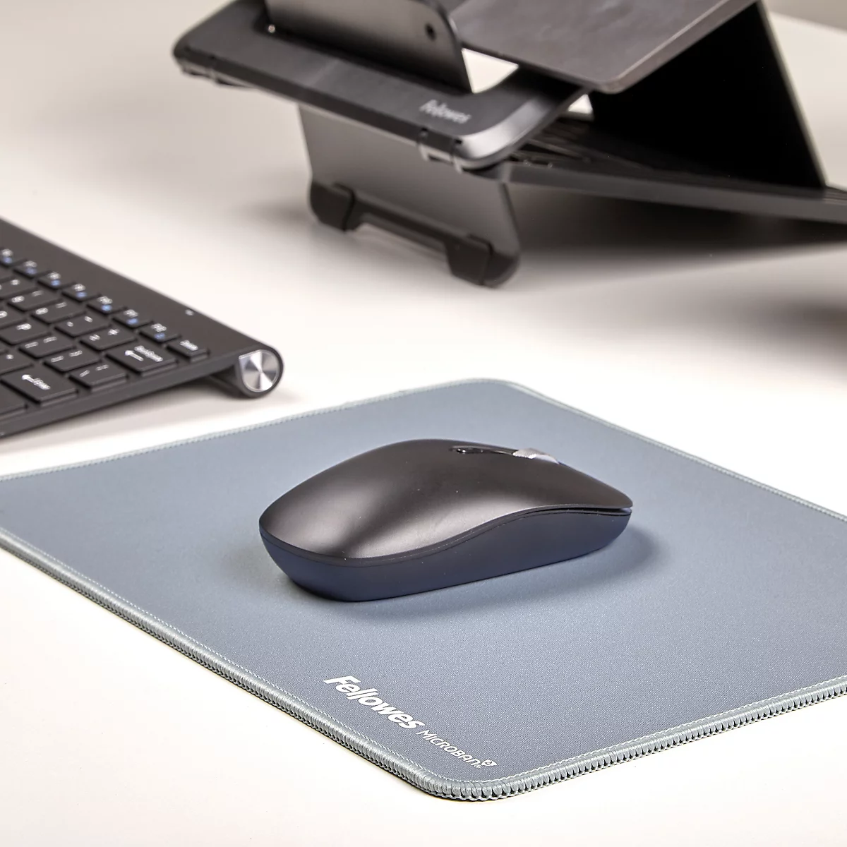Blaues rechteckiges Mousepad, Marke Fellowes. Geringeltes Muster am Rand.