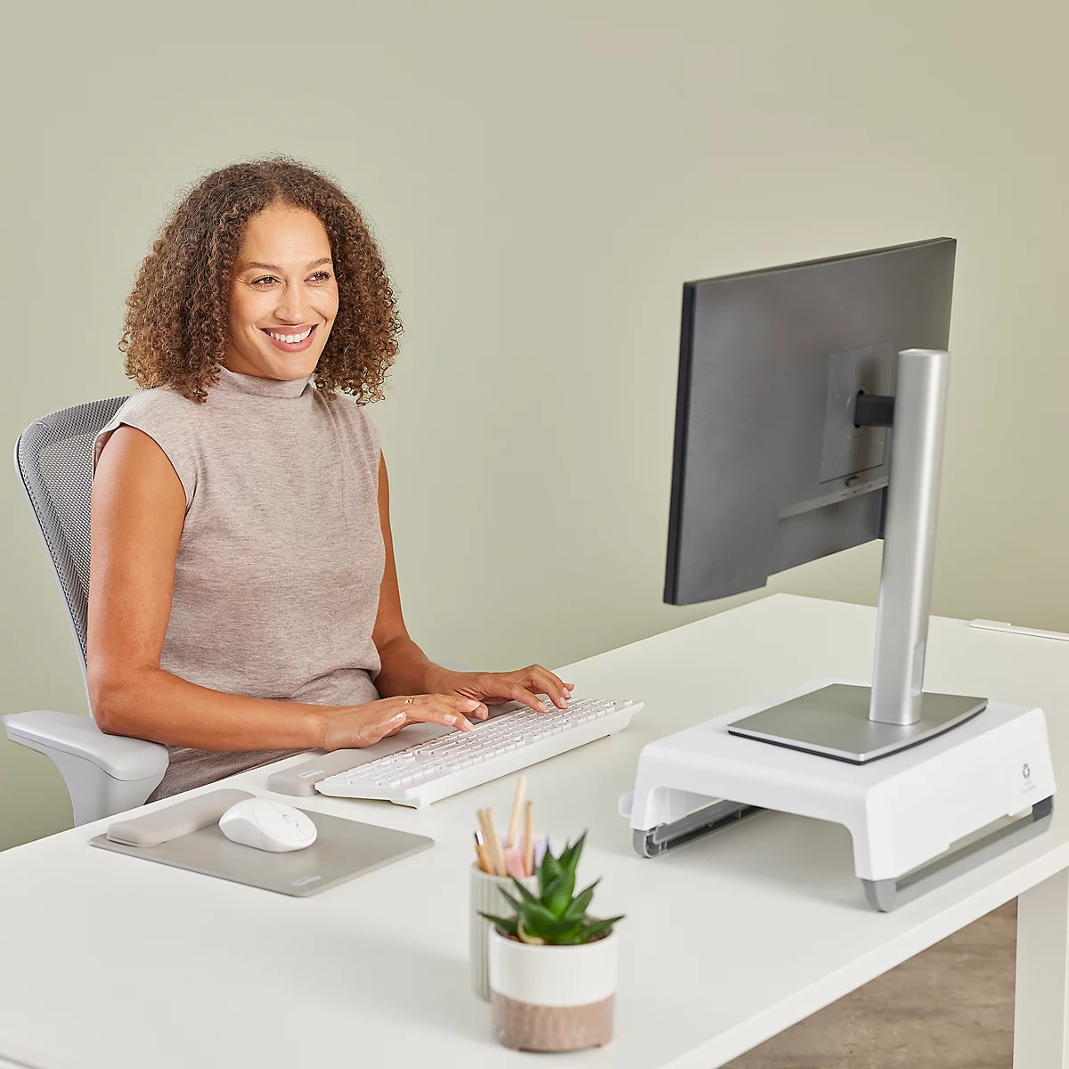 Femme travaillant à un bureau. Clavier, souris et repose-poignet sur un tapis gris.