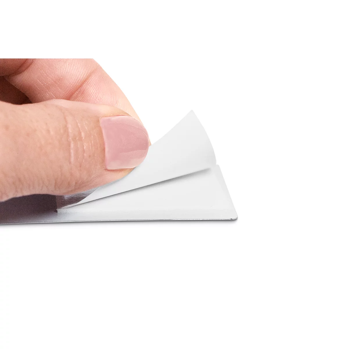 Hand lifting the corner of a white paper sheet. Fingernails delicately pink, light background.