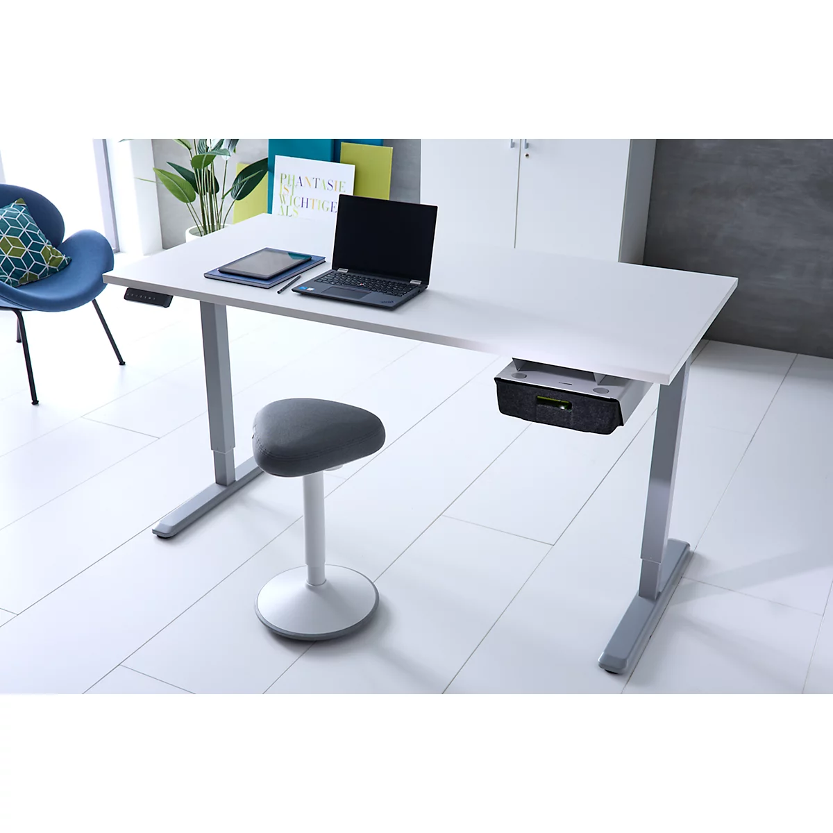 Ein moderner, weißer höhenverstellbarer Schreibtisch mit Laptop, Tablet und einem grauen ergonomischen Hocker.