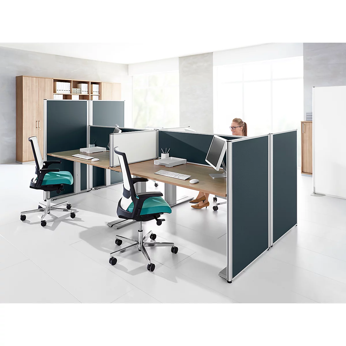 Office with workstations: desks, chairs, partitions. A woman working on the PC.