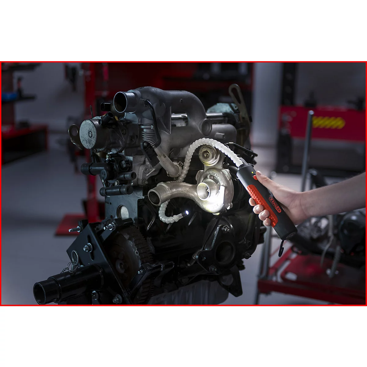 Ein Mechaniker untersucht mit einer Lampe einen Motor.