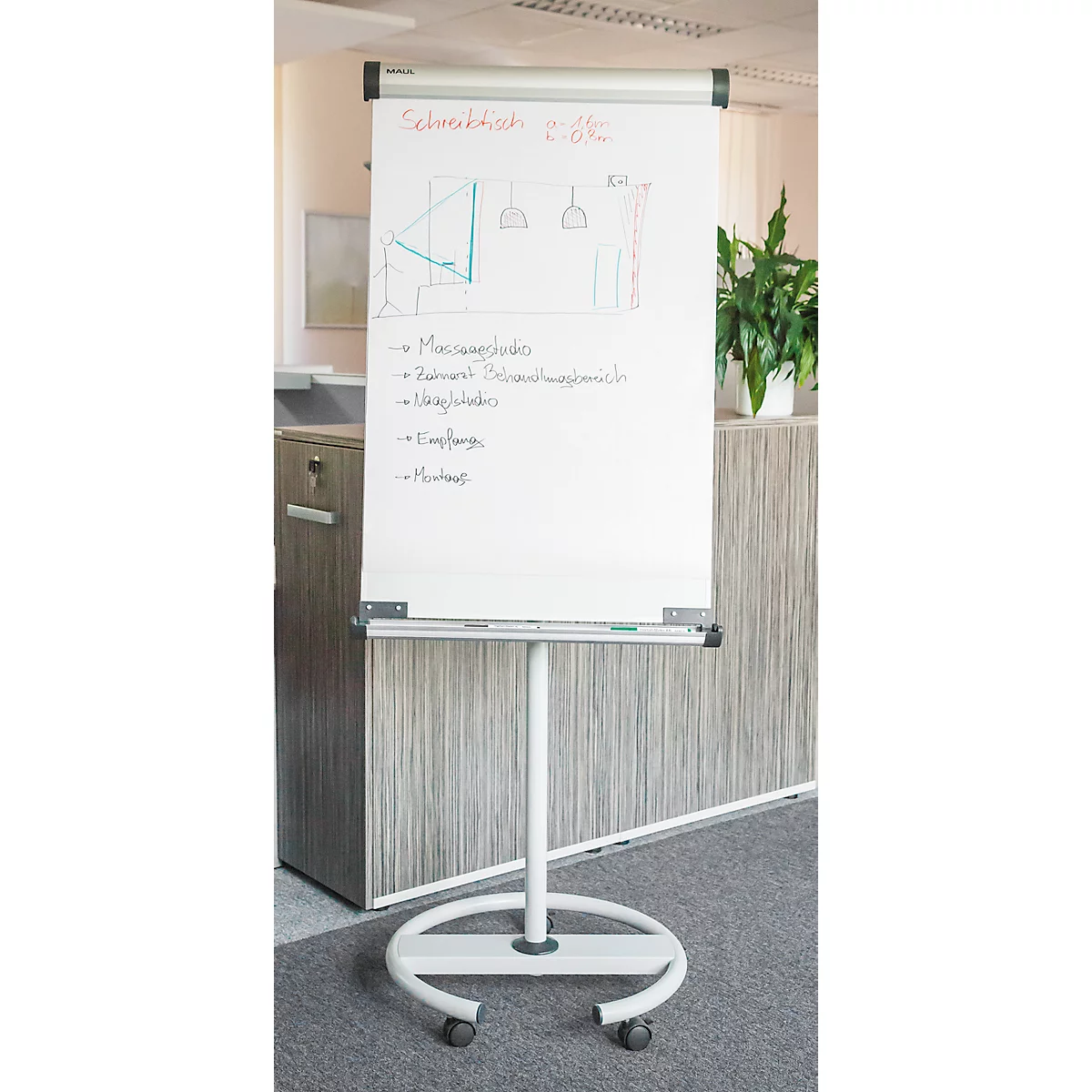 Tableau blanc avec dessins et notes, sur un pied à roulettes, au bureau.