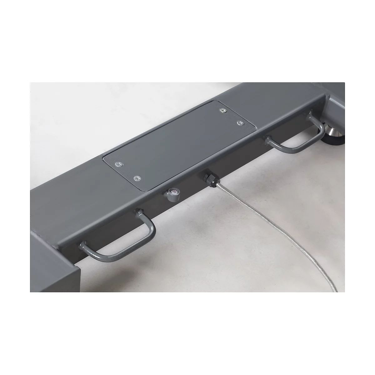 Close-up of a grey metal part. Handles, screws and a cable are visible.