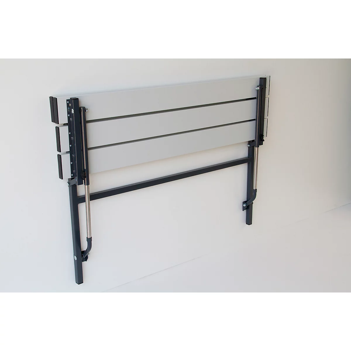 Grey folding table mounted on the wall with black frame. The table is folded.