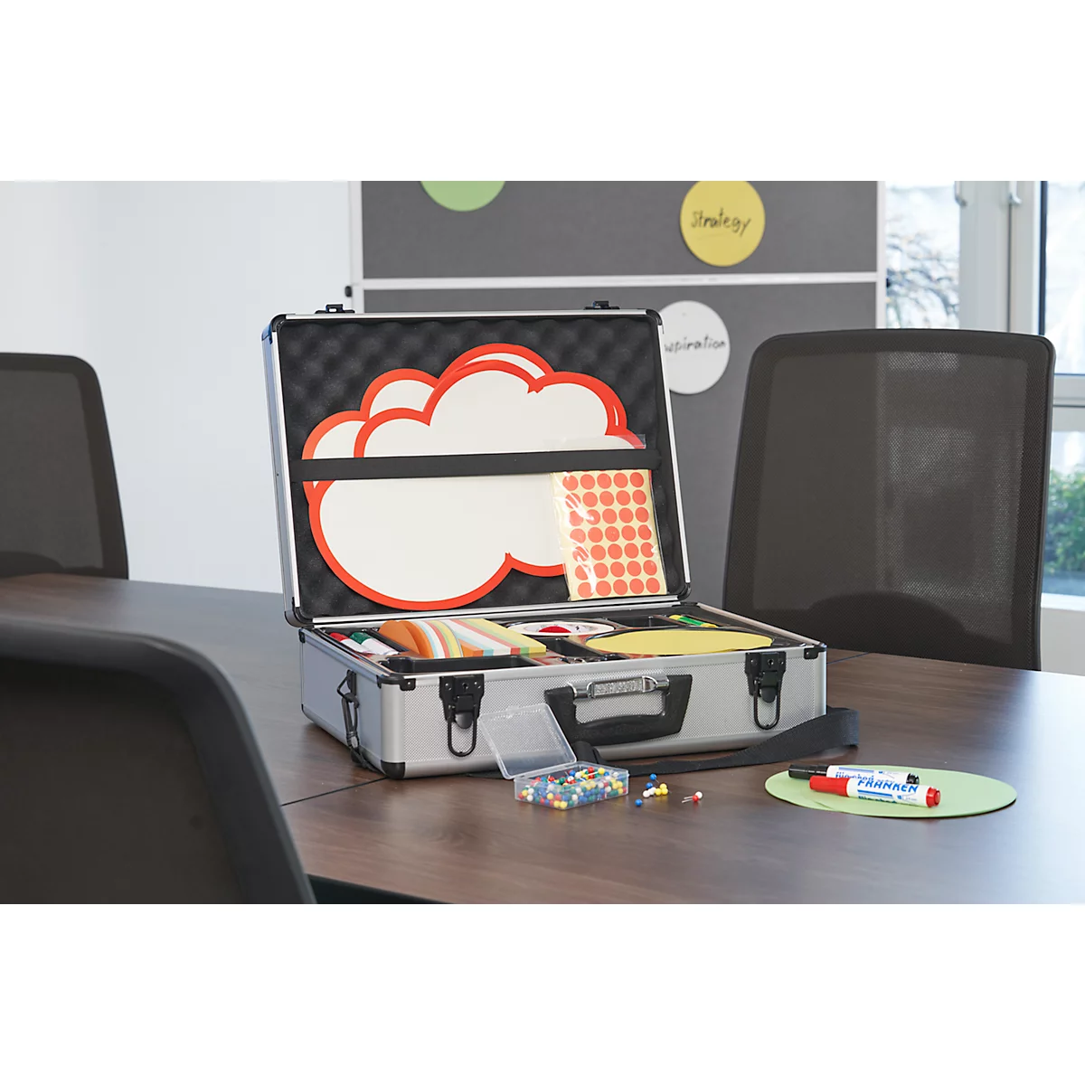 Open silver briefcase with various conference supplies. Including a cloud whiteboard and colorful pens.