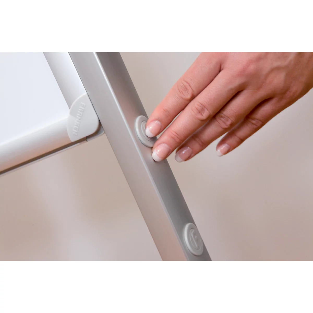 Close-up of a hand pressing a button on a silver metal frame.
