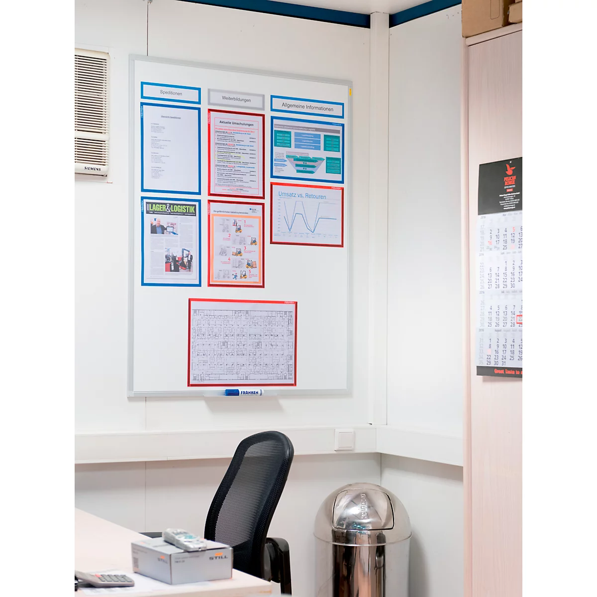 Whiteboard with posters and diagrams on a white wall. Office with chair, table, trash can.