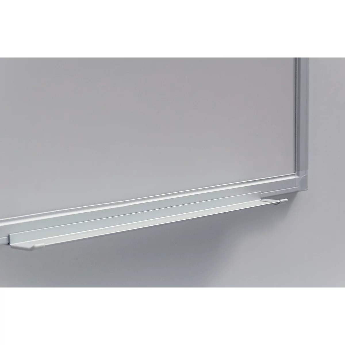 Close-up of a white board with an aluminum frame and storage tray. The board is slightly lit.