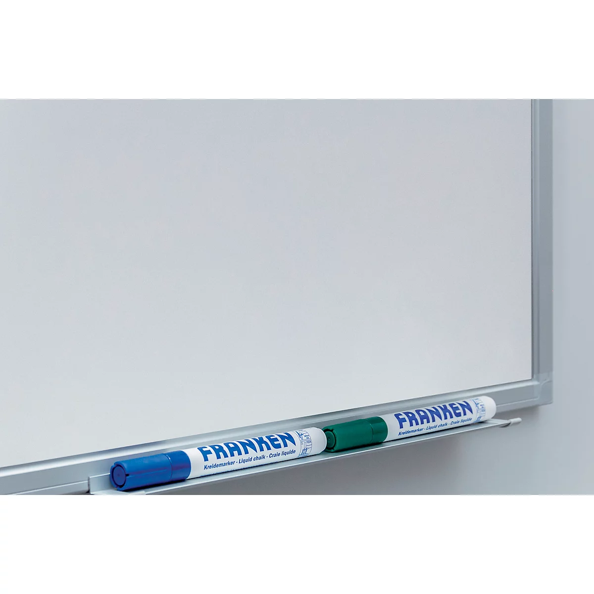 White whiteboard with silver frame and pen holder. Blue and green pens are in the holder. Brand name: FRANKEN.