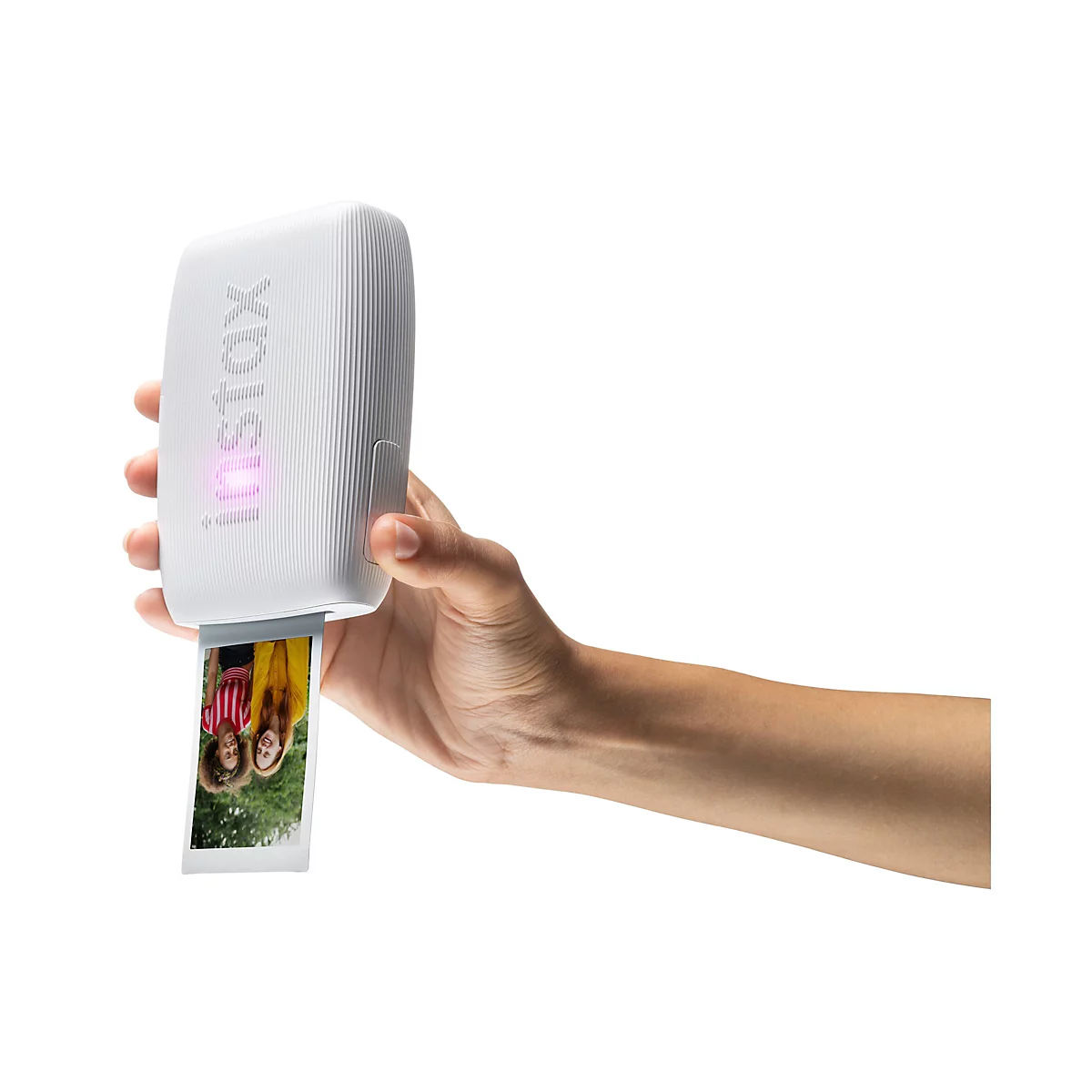 Person hält einen weißen Instax-Fotodrucker mit einem herauskommenden Foto, auf dem zwei Frauen zu sehen sind.