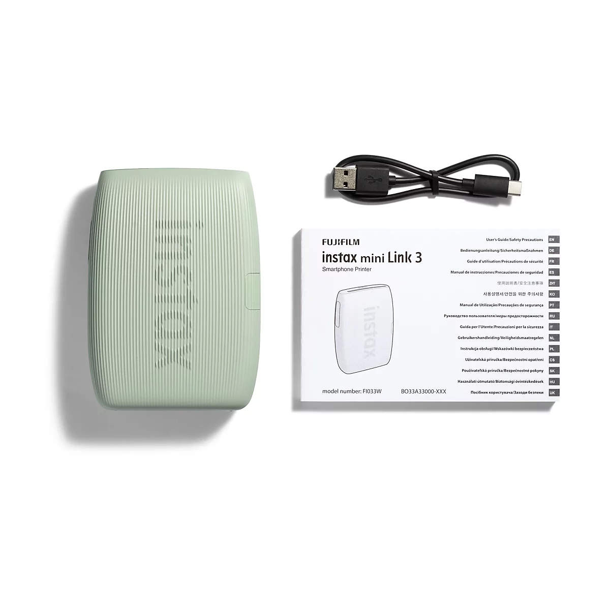 Hellgrüner instax mini Link 3 Smartphone-Drucker, Ladekabel und Bedienungsanleitung vor weißem Hintergrund.