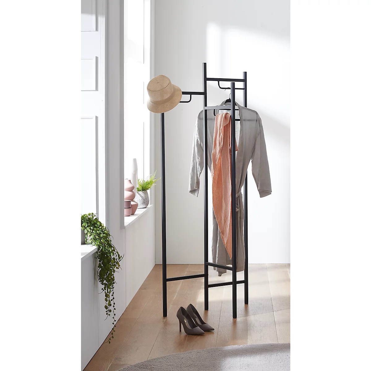 Schwarzer Kleiderständer mit Hut, Schal, Bademantel und Schuhen.