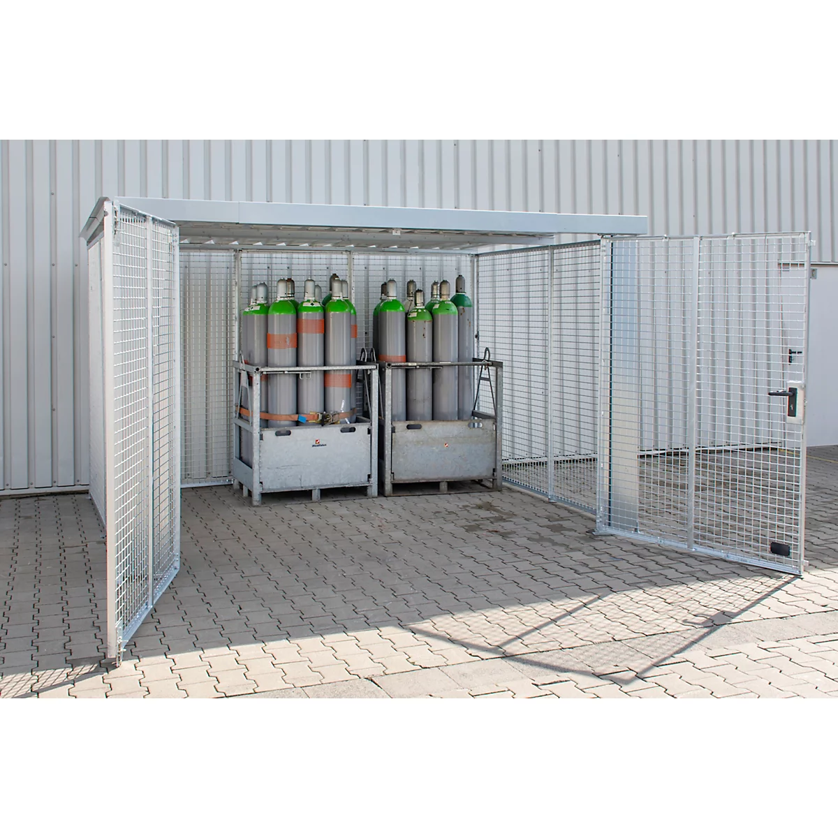 Sichere Gasflaschen im metallenen Schutzhaus. Gittertüren geöffnet, dahinter Flaschen in Transportgestellen.