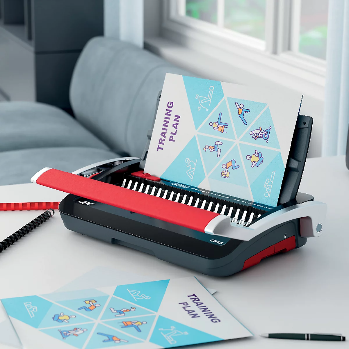 Une relieuse rouge et noire avec un modèle de plan d'entraînement. D'autres plans et des stylos sont sur la table.