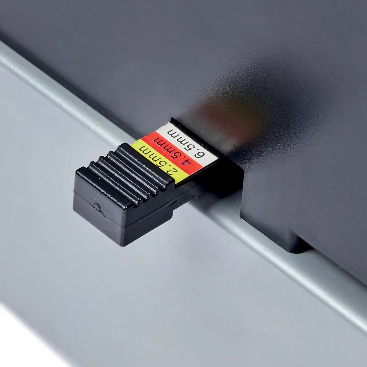 Gros plan sur une pièce noire et côtelée avec des marquages colorés et lettrage: 2.5mm, 4.5mm, 6.5mm.