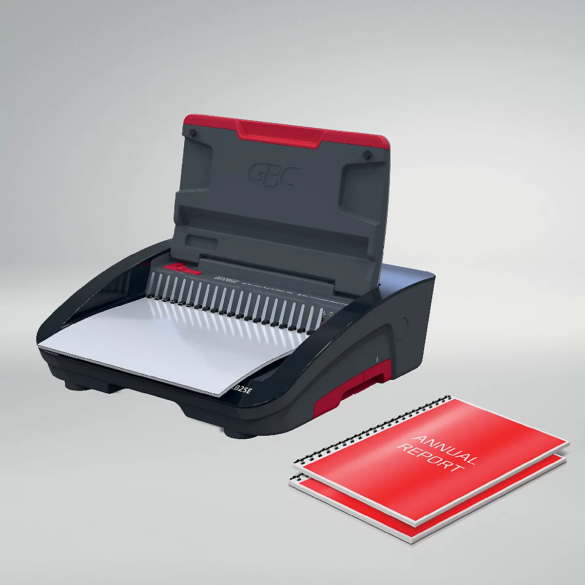 Een zwarte en rode GBC bindmachine met deksel open. Daarnaast liggen twee rode brochures met de tekst "ANNUAL REPORT".