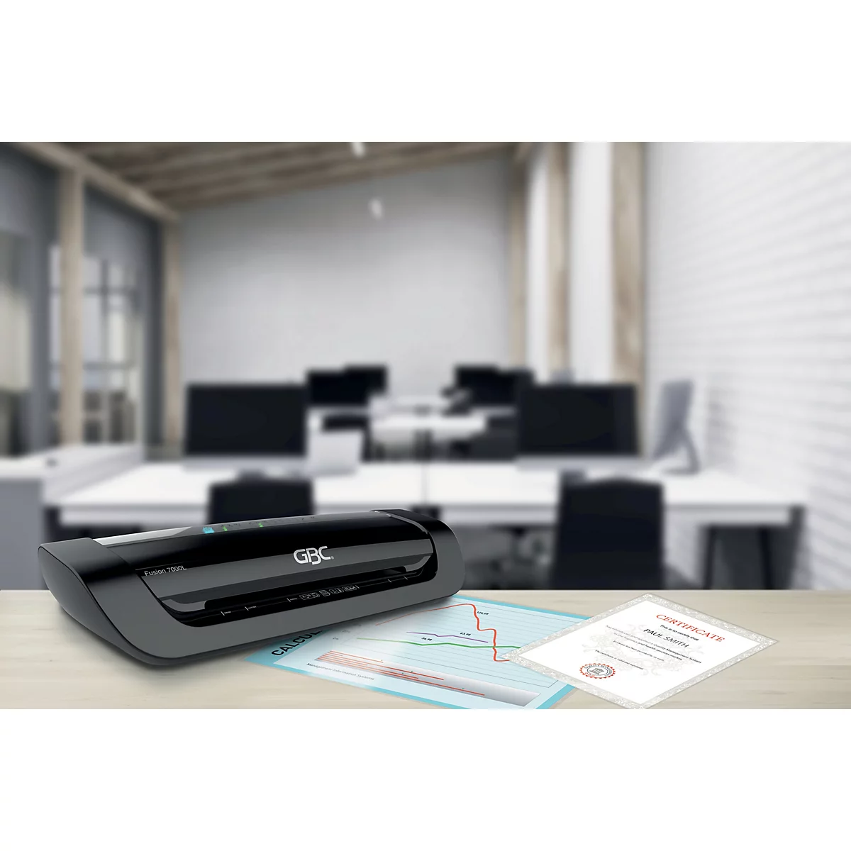 Une plastifieuse noire de la marque GBC sur un bureau. Un bureau avec des ordinateurs et des documents en arrière-plan.