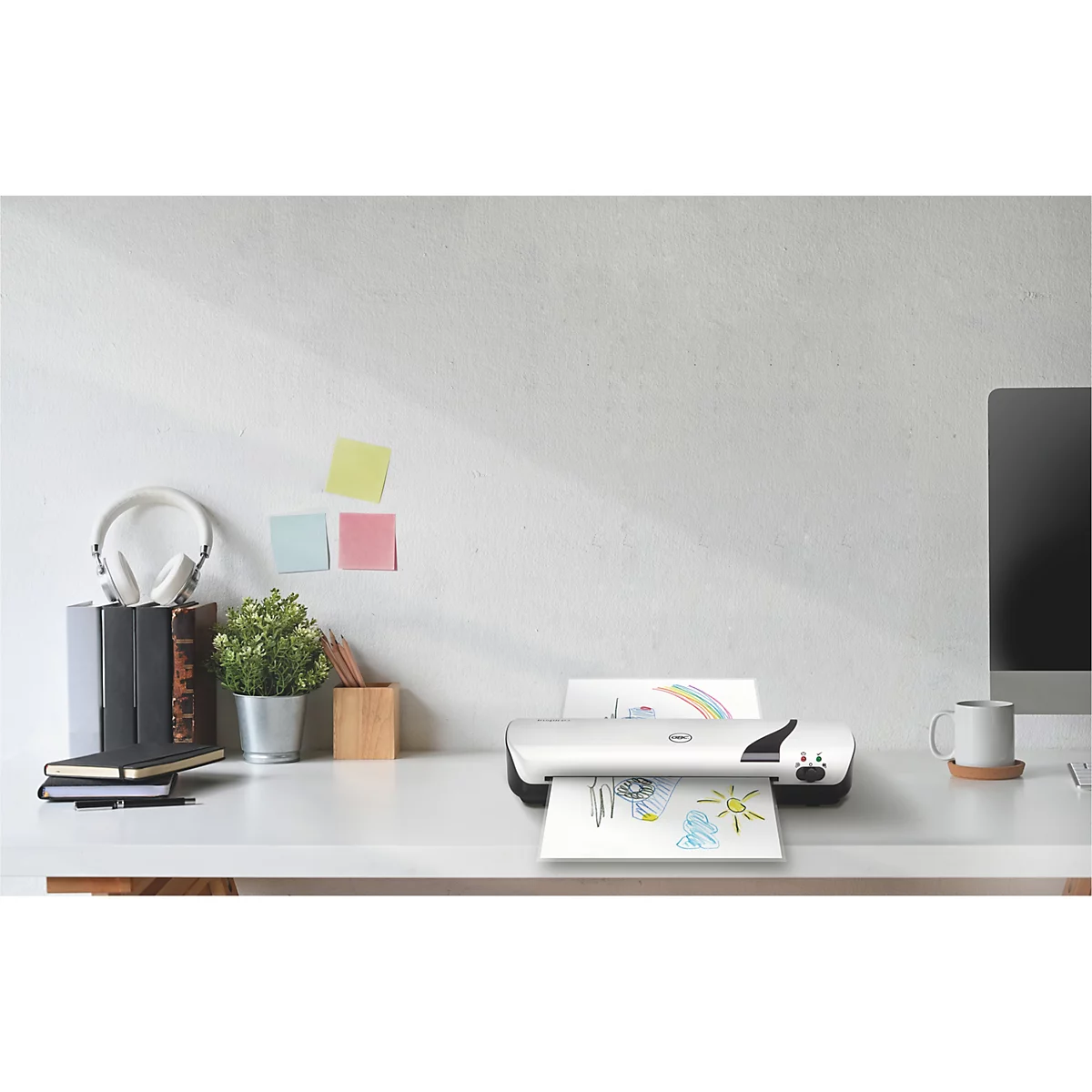 Bureau met printer, papier met kindertekening, koptelefoon, notitieboekje en koffiekopje.