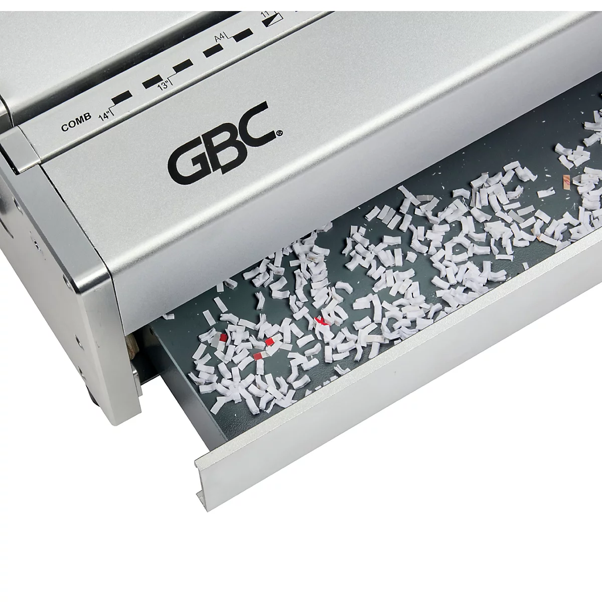 Close-up van een zilverkleurige papierversnipperaar met de opvangbak uitgetrokken, gevuld met versnipperde papieren stukken.