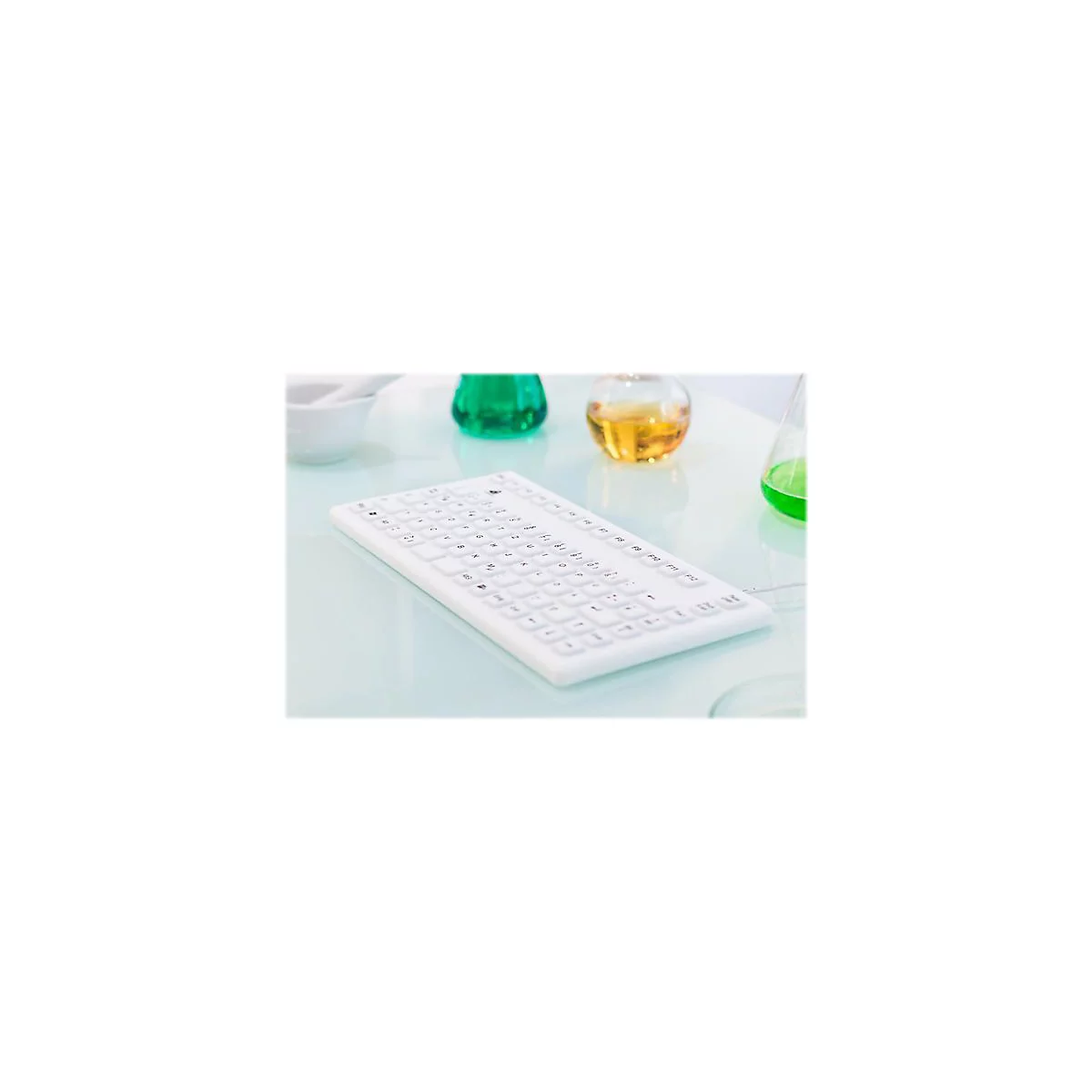Weiße Silikon-Tastatur auf einem Labortisch neben Reagenzgläsern.