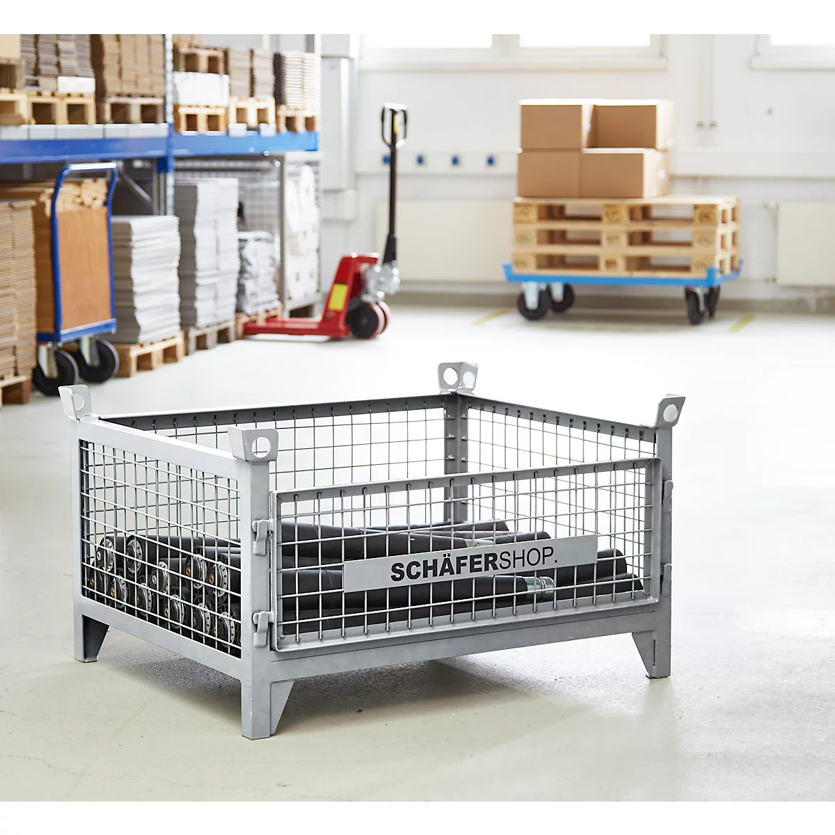 Graue Gitterbox mit schwarzem Inhalt, vor einem Lager. Auf der Box steht „SCHÄFERSHOP“.