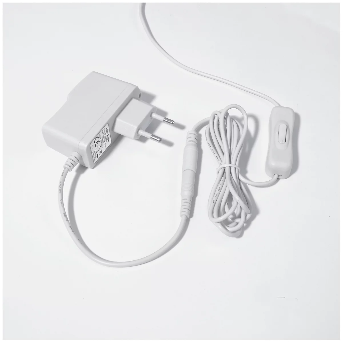 Ein weißes Netzteil mit Stecker und Kabeln, auf weißem Hintergrund.