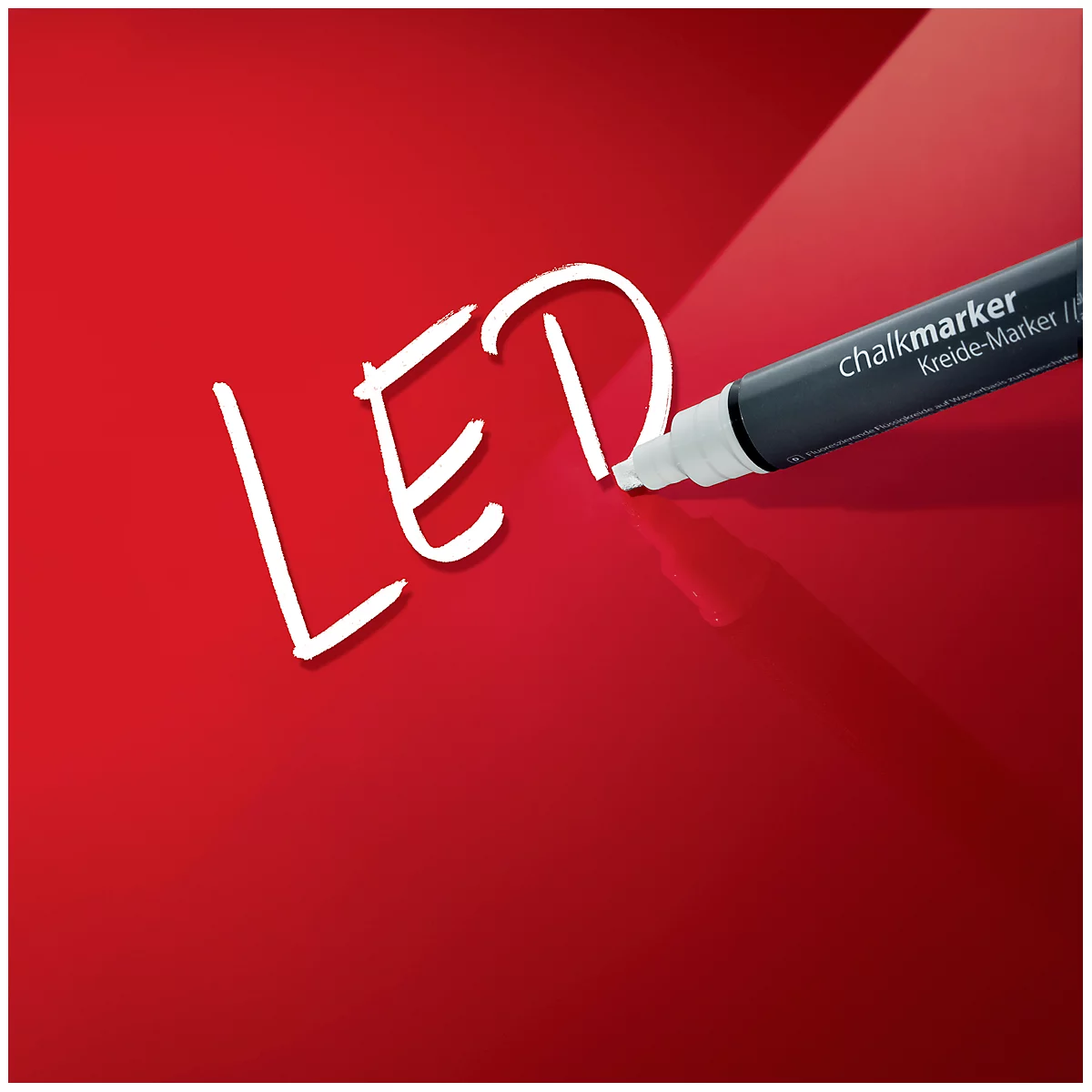 Ein schwarzer Kreidemarker schreibt auf rotem Grund das Wort LED. Der Marker ist ein Chalkmarker/Kreide-Marker.