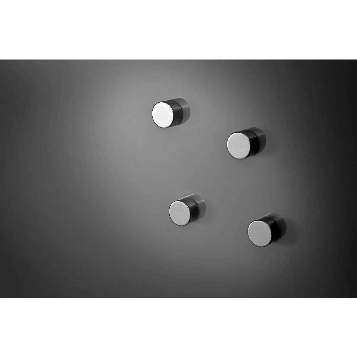 Four cylindrical magnets, two silver surfaces, dark background.