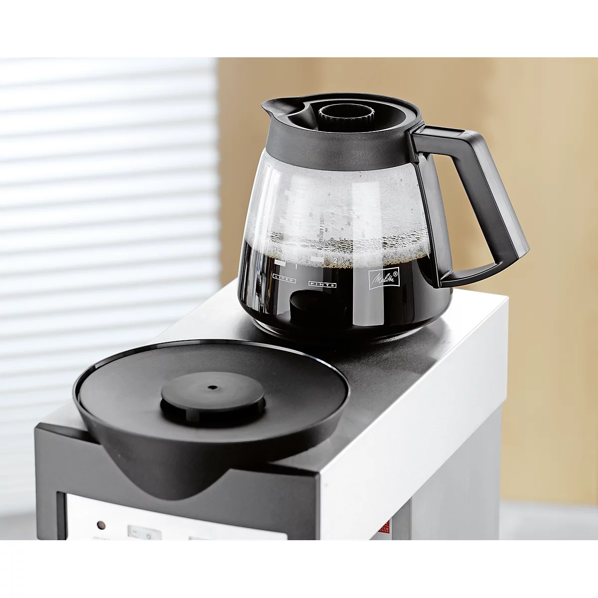 Glass coffee pot with freshly brewed coffee on a coffee machine. Black jug with handle.