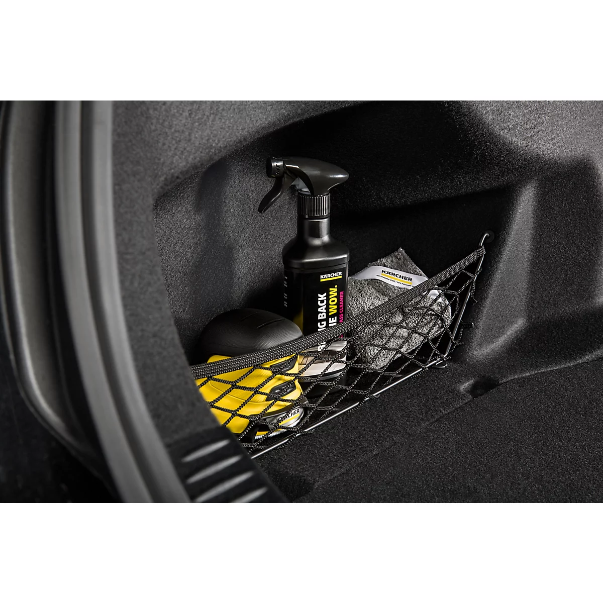 Gros plan d'un espace de rangement de voiture avec des produits de nettoyage. Un vaporisateur est posé à côté d'éponges et de chiffons en microfibre.