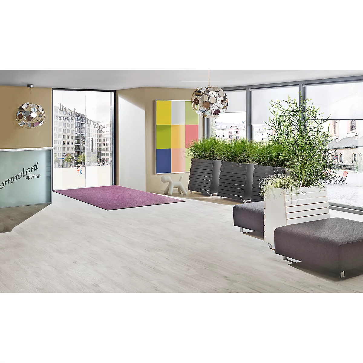 Een heldere, moderne receptie met grote ramen en planten. Er ligt een paars tapijt op de vloer.