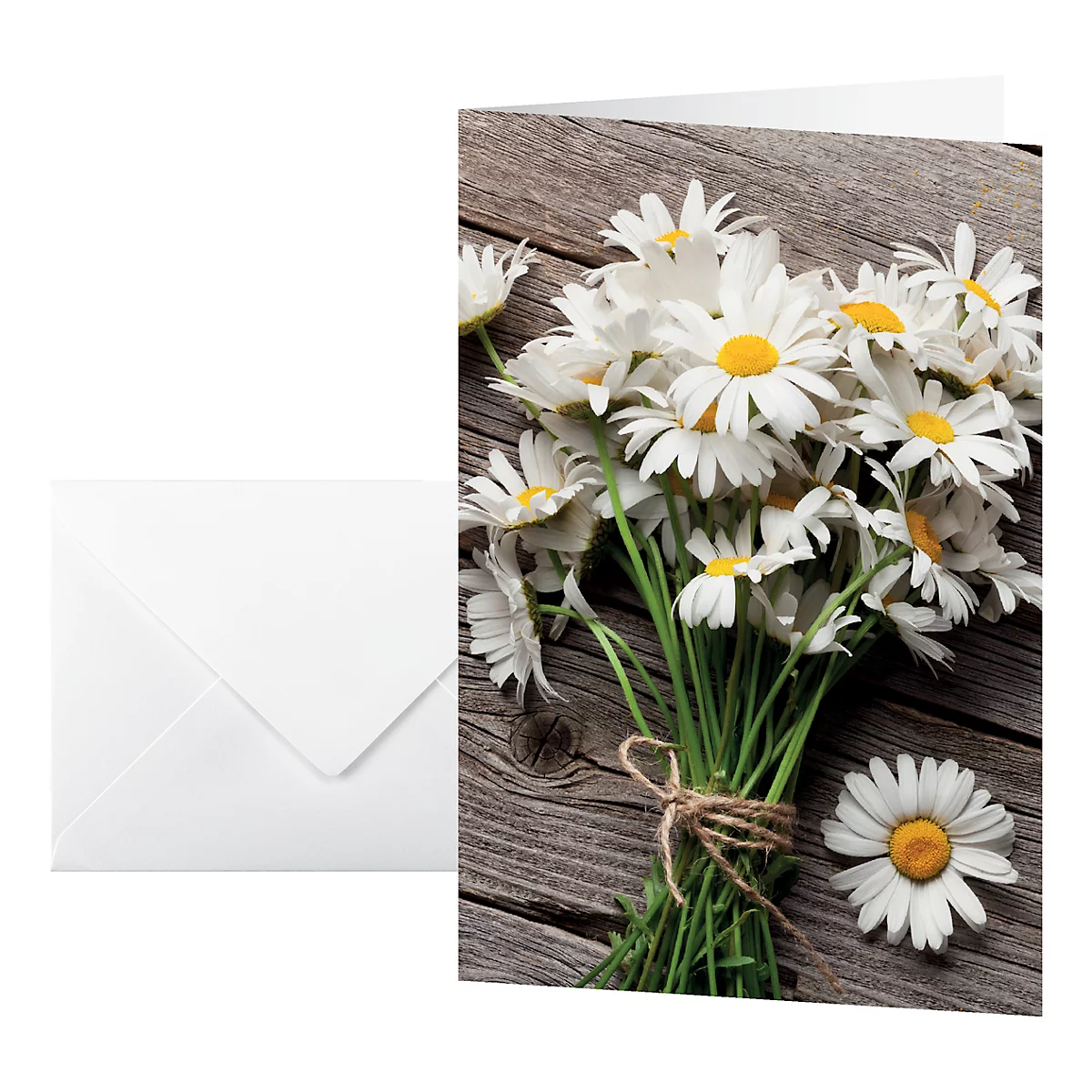 Greeting card with daisies next to a white envelope. On rustic wood.
