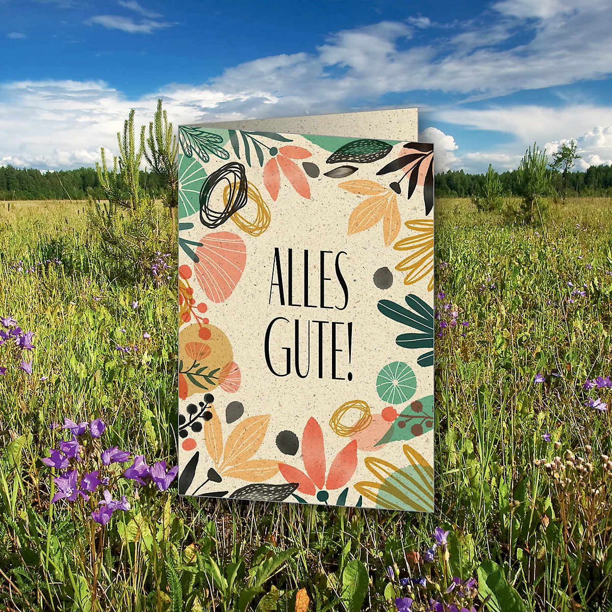 Card with floral frame and lettering: ALL THE BEST! in the grass under a blue sky.