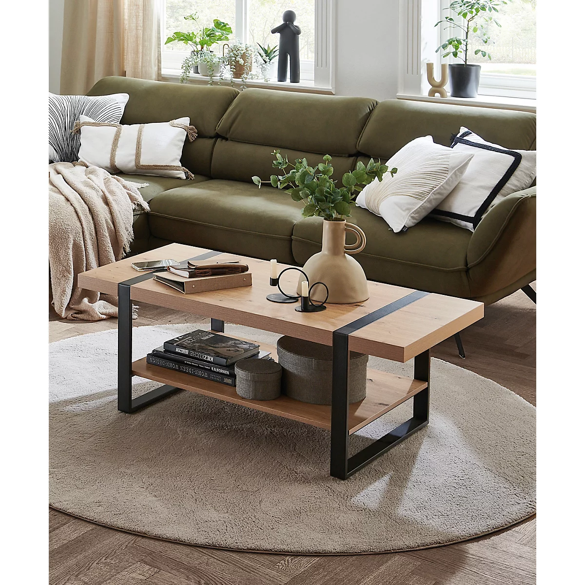 Wohnzimmer mit Couch, Beistelltischen und Kaffeetisch. Holz und Metall Kombination, grüne Couch mit Kissen. Pflanzen und Dekorationen.