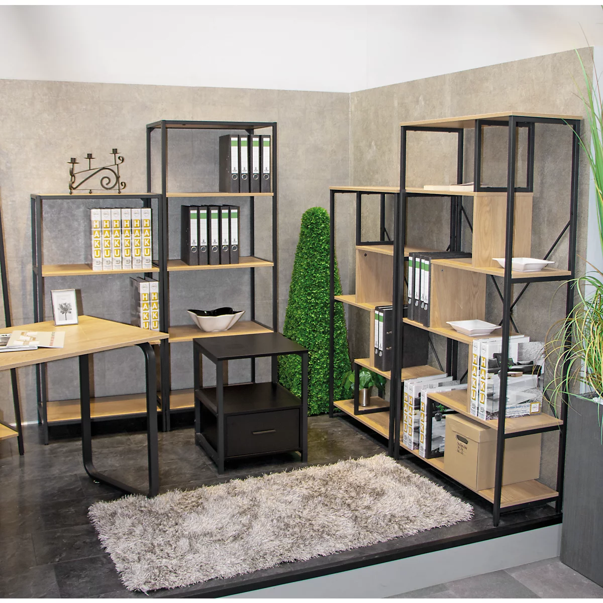 Kantoor met planken, bureau, bijzettafel, vloerkleed en decoratie. Lichte houtlook, zwarte stalen frames.