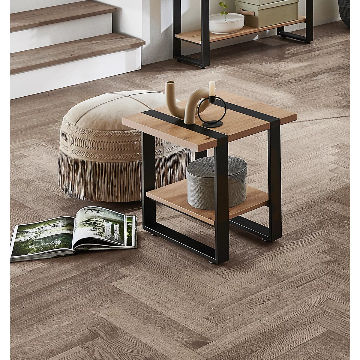 Table en bois avec cadre en métal, à côté un pouf, un magazine et de la décoration. Autres meubles en arrière-plan.