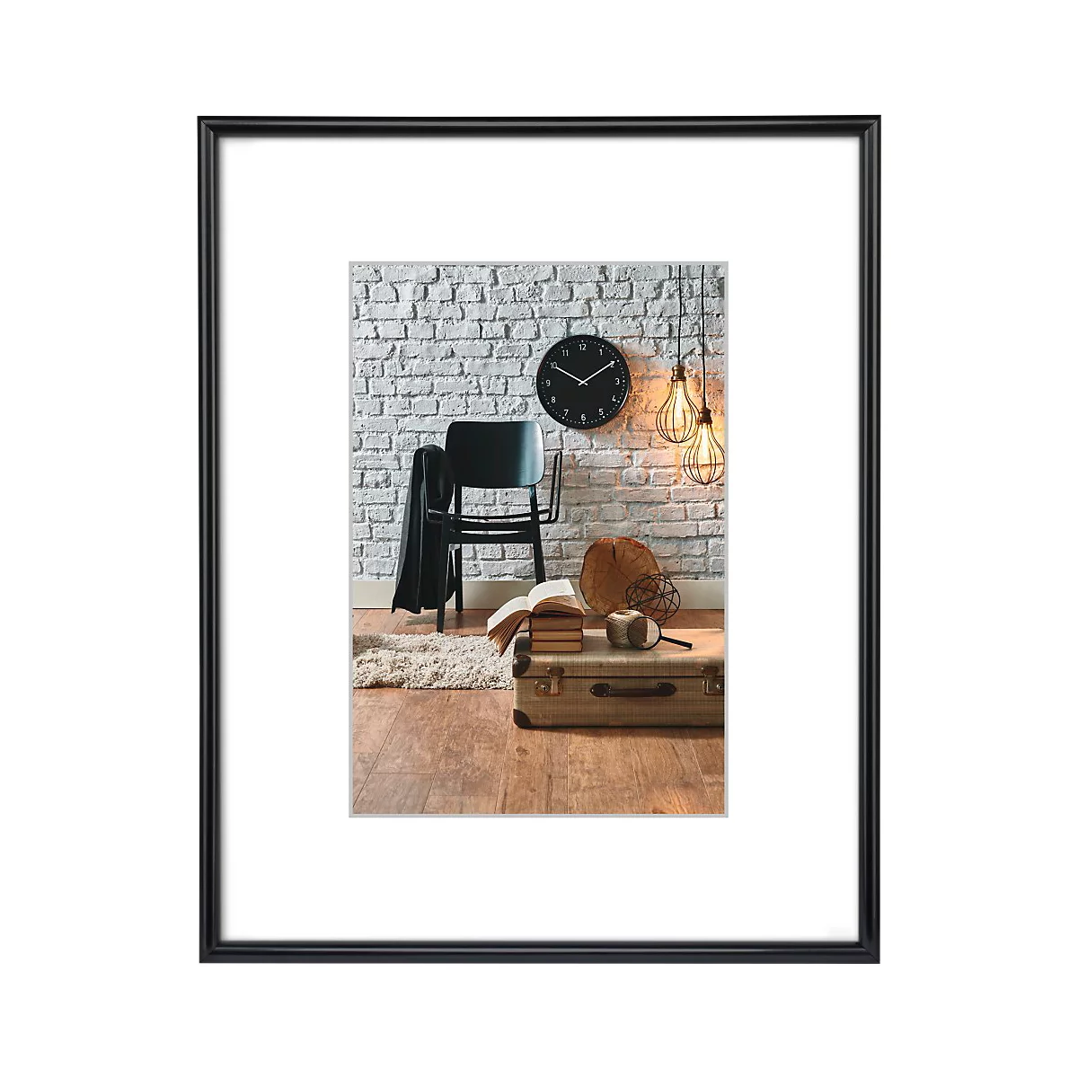 Ein Bild in einem schwarzen Rahmen. Es zeigt ein Zimmer mit Backsteinmauer und Uhr. Ein Stuhl, Koffer, Bücher, Lampen und ein Teppich sind zu sehen.