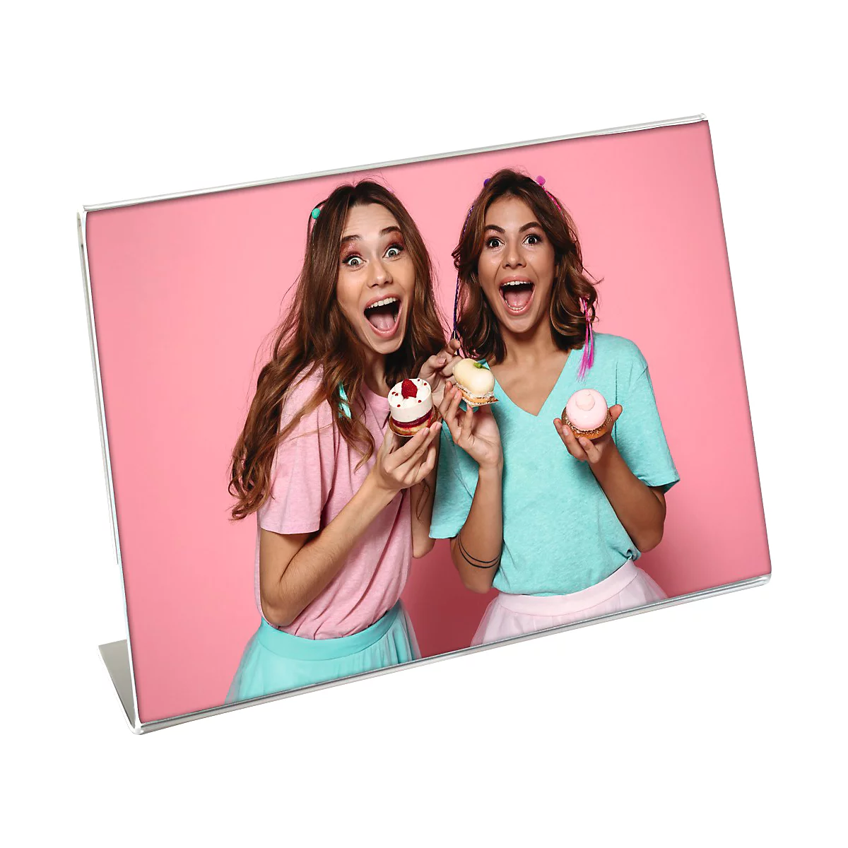 Zwei Frauen mit Cupcakes, lachen vor rosa Hintergrund.