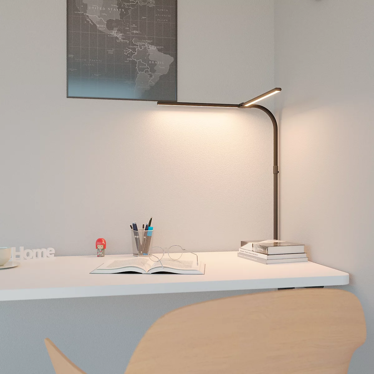 Schreibtisch mit Lampe, Notizbuch, Stiften und Globuskarte an der Wand.