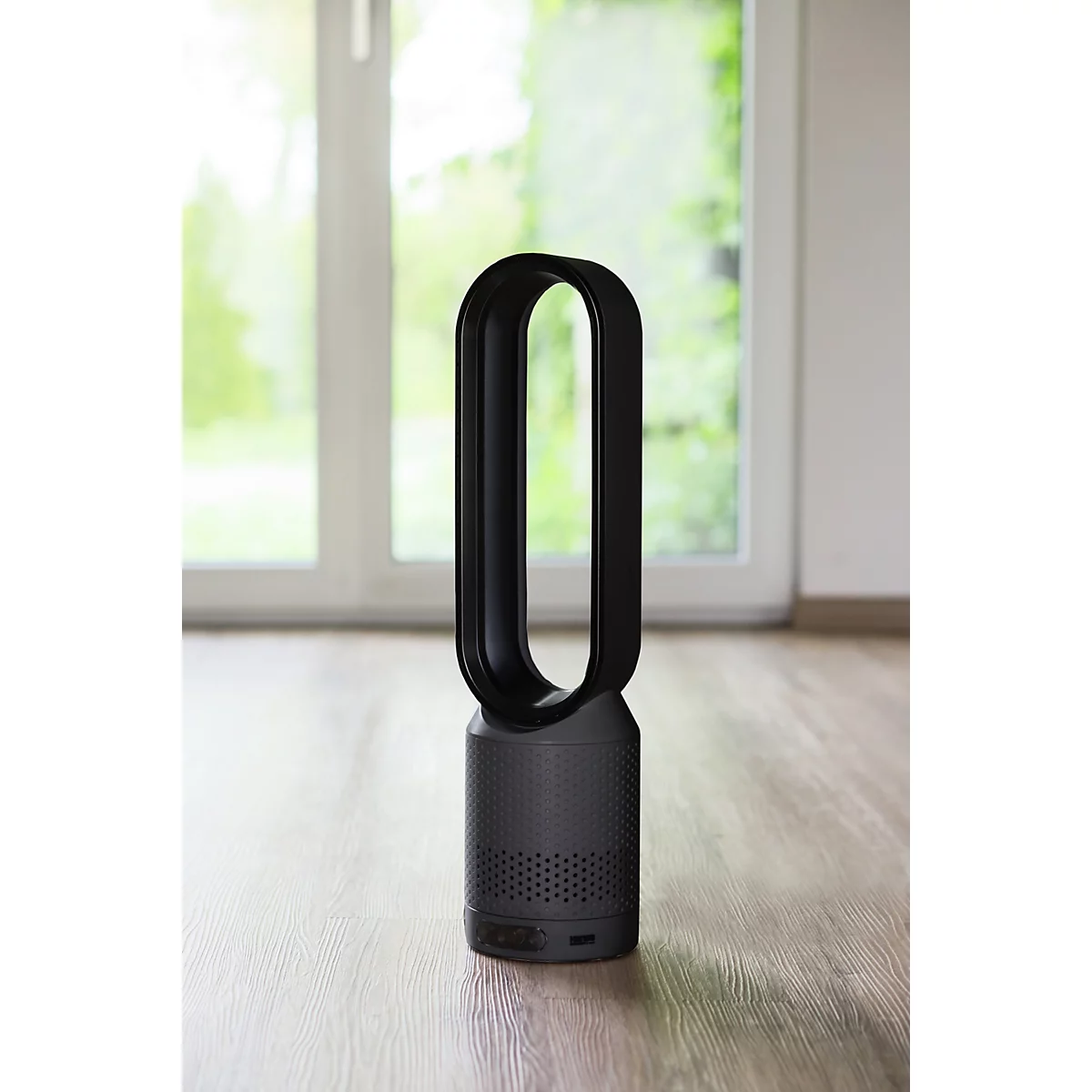 Zwarte torenventilator met ovaal frame, staand op houten vloer, achtergrond raam.