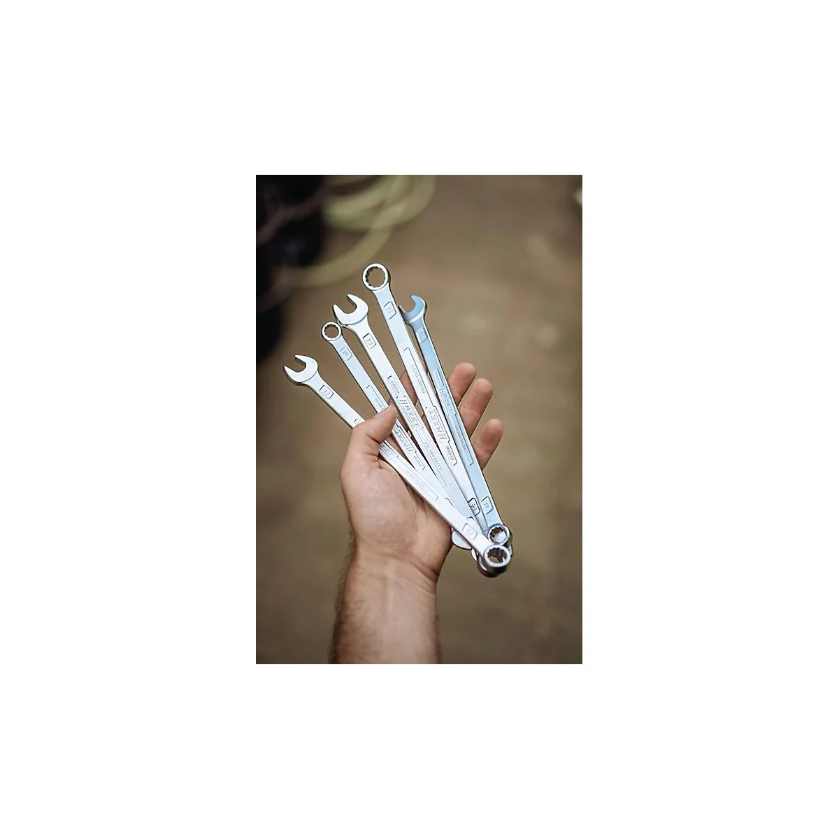 Une main d'homme tenant une sélection de clés. Les outils sont argentés.