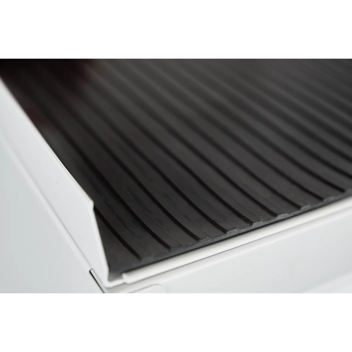 Close-up of a black, grooved surface resting on a white structure.