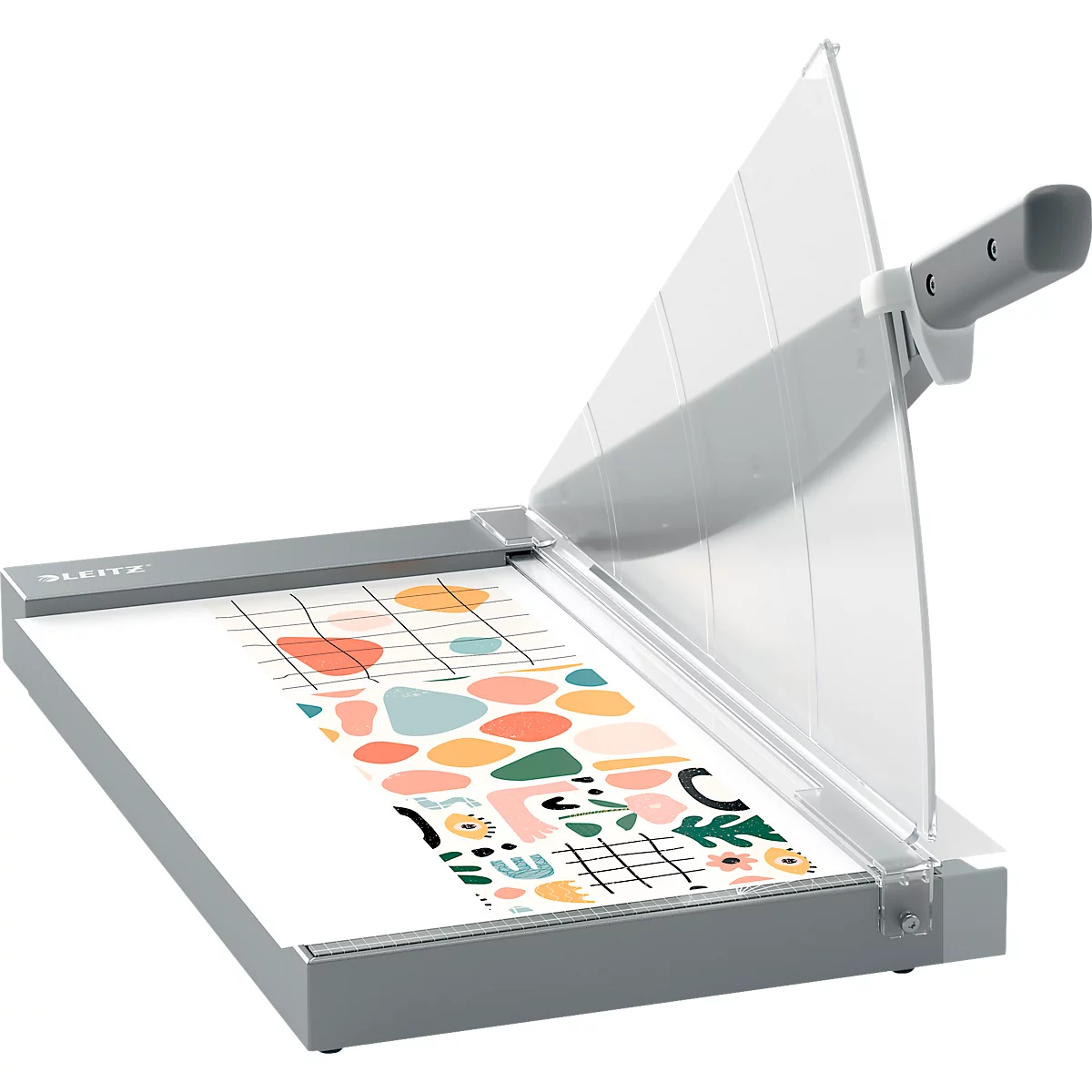 Grauer Papierschneider mit transparentem Schutz. Auf dem Papier: bunte Muster.