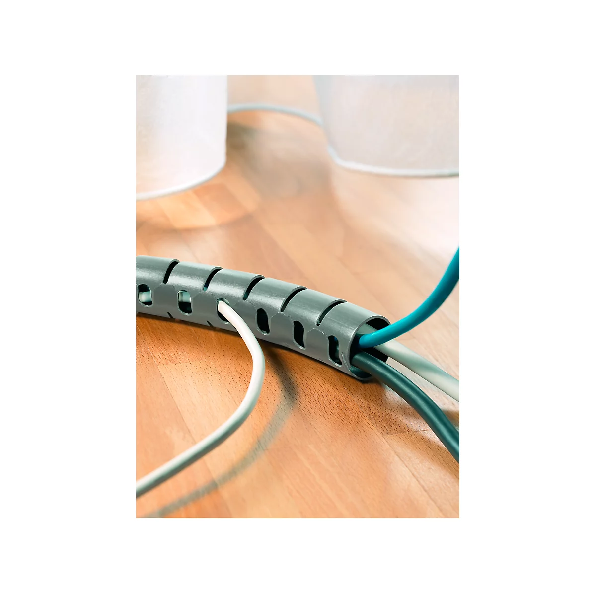 Grey cable spiral on wooden floor. Several colored cables are guided through it.
