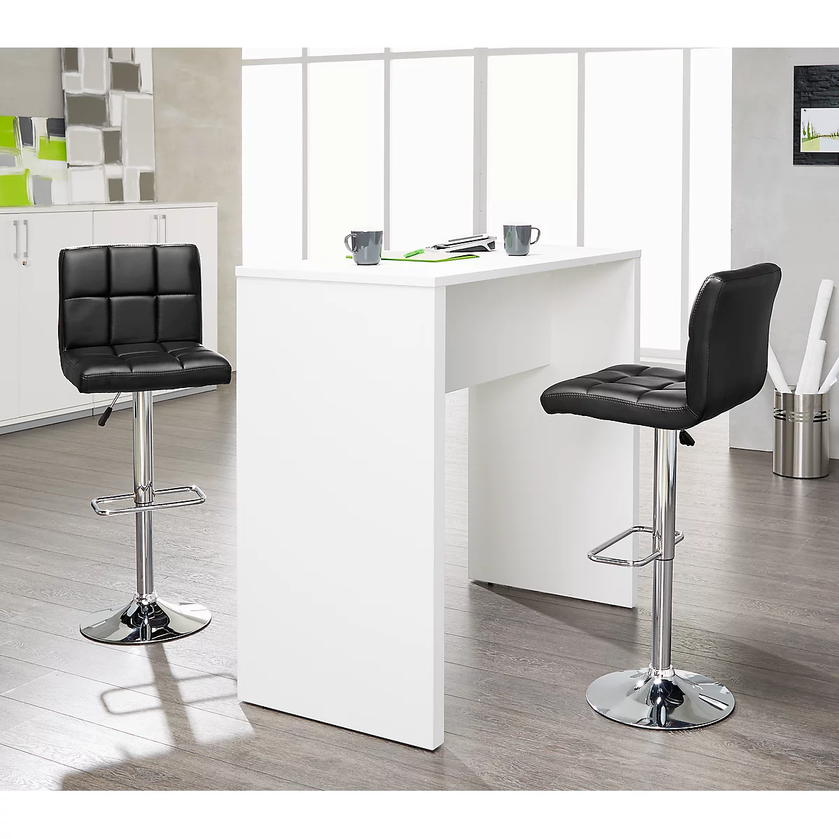 White bar table with two black bar stools. On the tabletop are two gray mugs and pads.