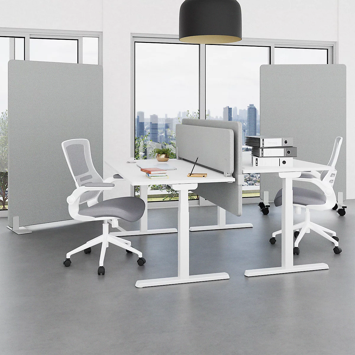 Büro mit weißen Schreibtischen, Stühlen und grauen Trennwänden. Blick auf die Fenster mit Skyline.